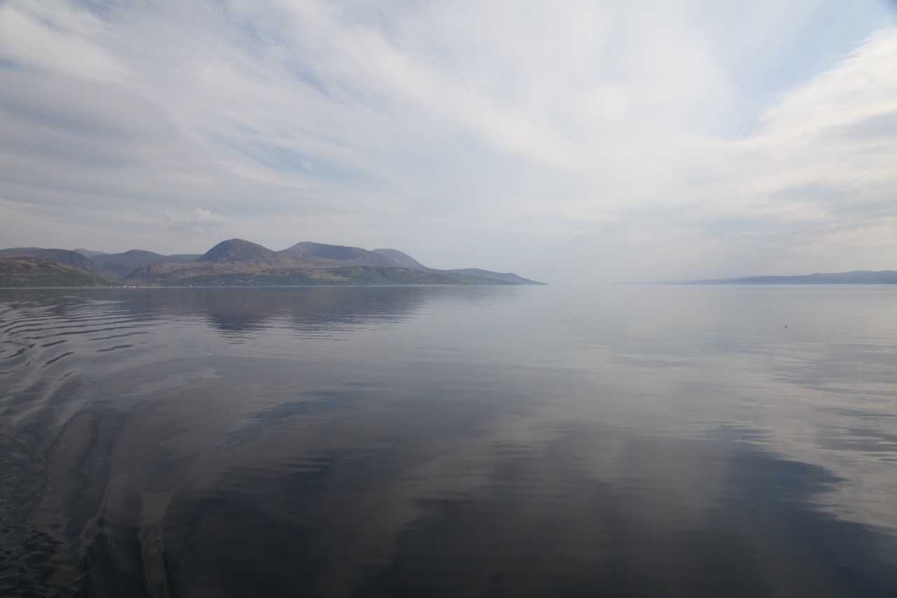 Beautiful view of glassy sea on a misty morning with mountains in background
