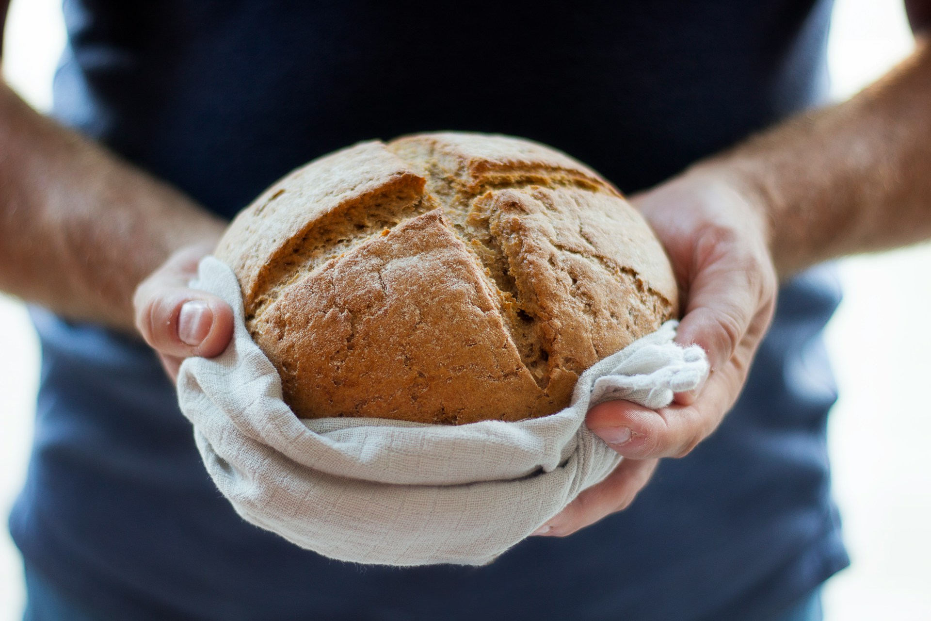 Hands holding a freshly baked loaf of sourdough bread