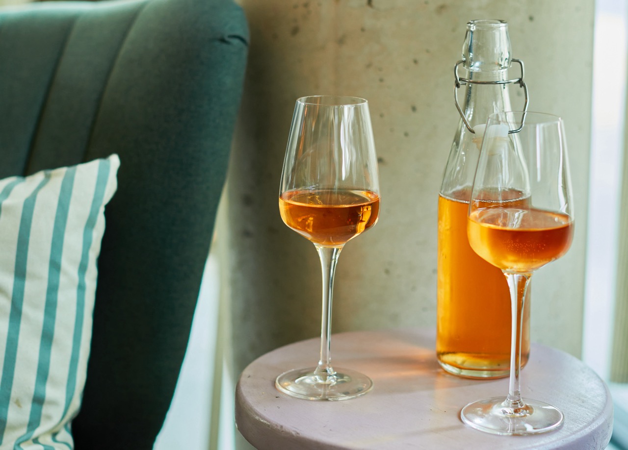 Bottle and two glasses of orange wine on small side table