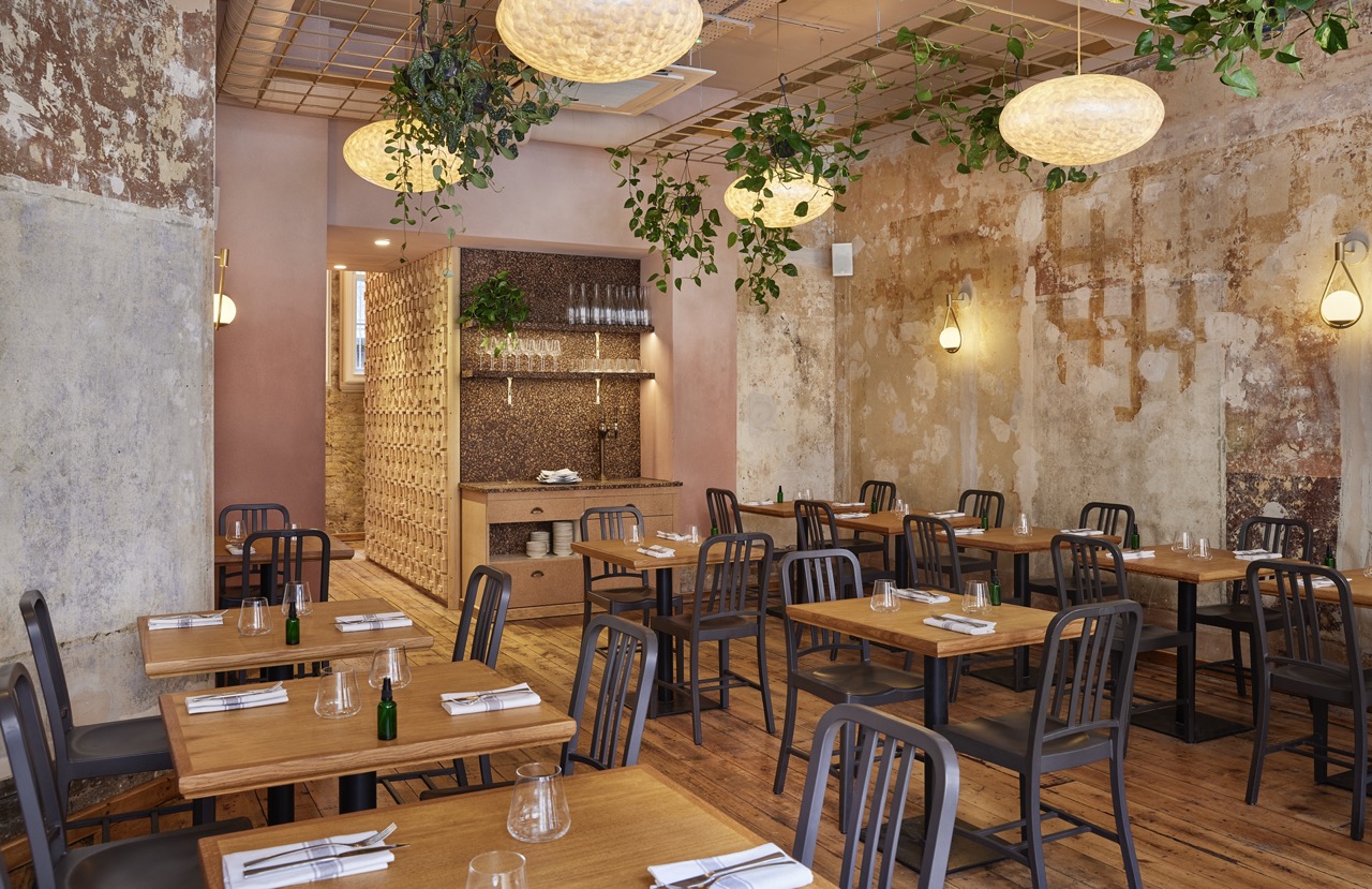 Apricity restaurant interior, with pink and gold decor and plants hanging from ceiling