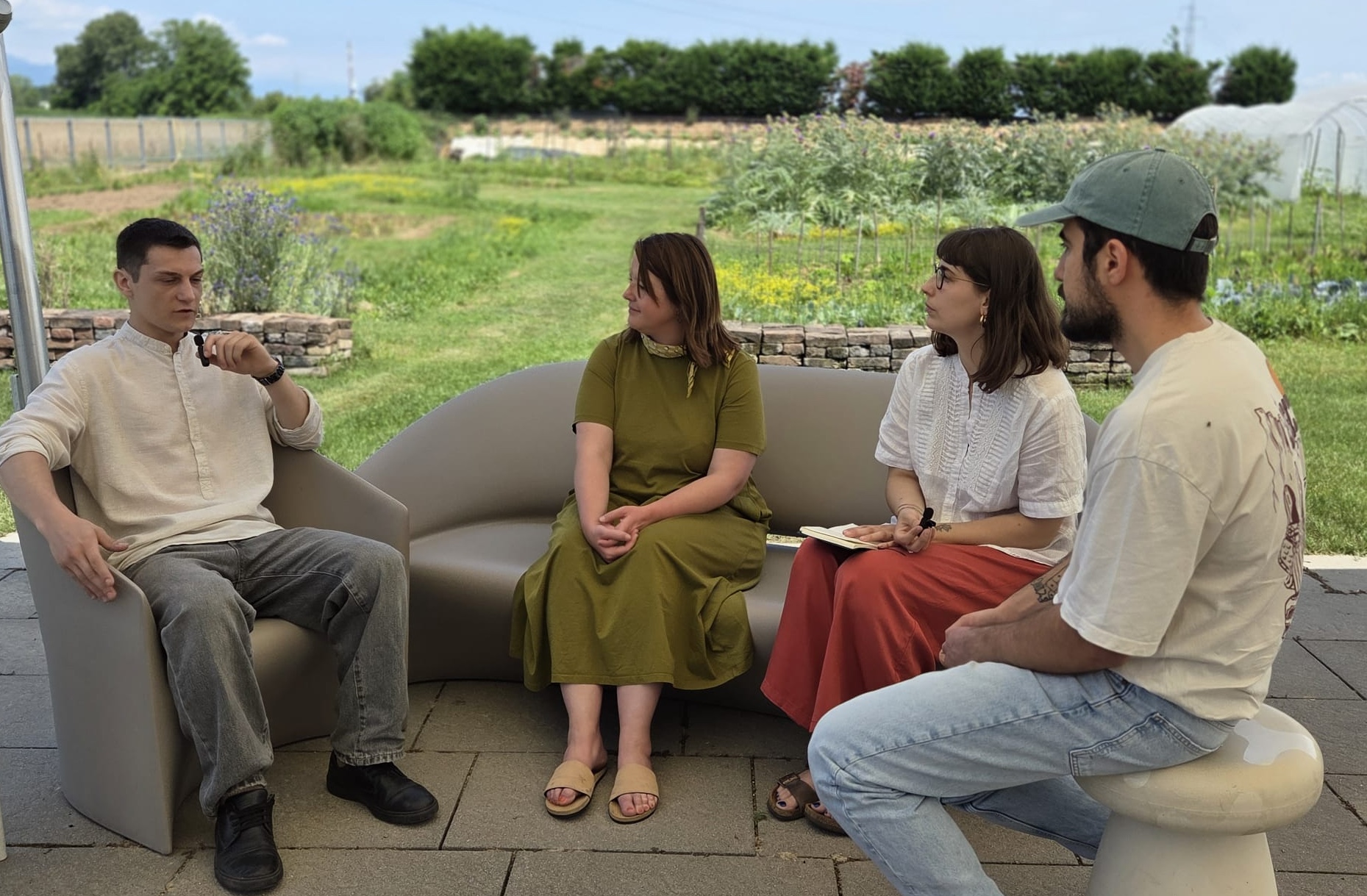 Juliane and Lucia of The SRA speaking with Fabio and Vicenzo of Casa Format under a canopy with the farm in the background
