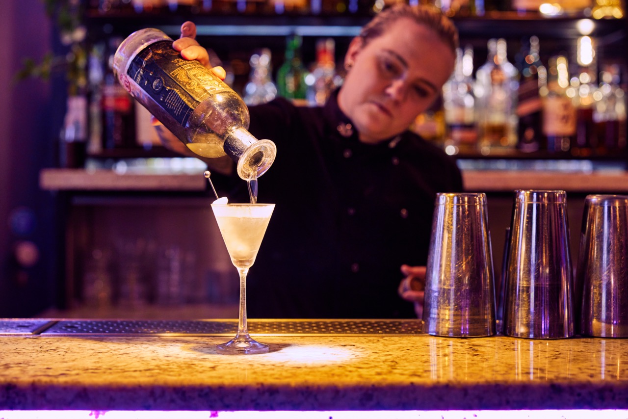 Bartender pouring a drink from a cocktail shaker at Eve Bar