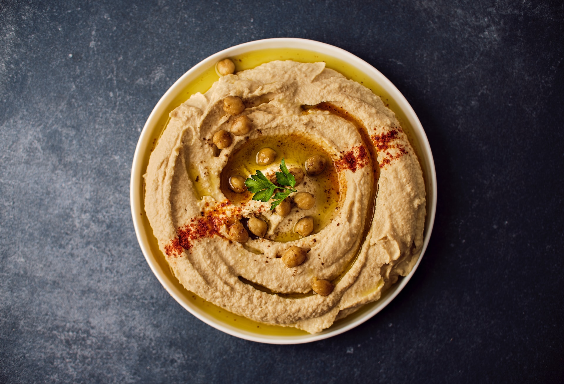 Overhead shot of bowl of hummus against dark background