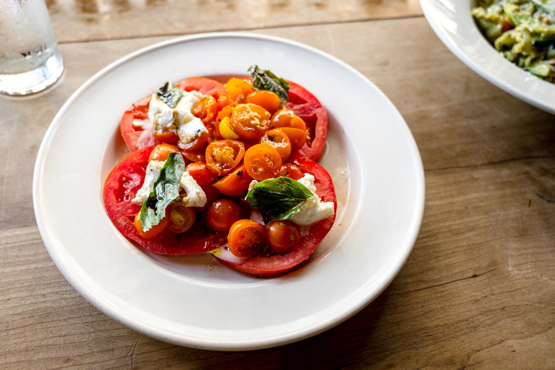 White plate with beef tomatoes, cherry tomatoes, basil and fresh mozzarella