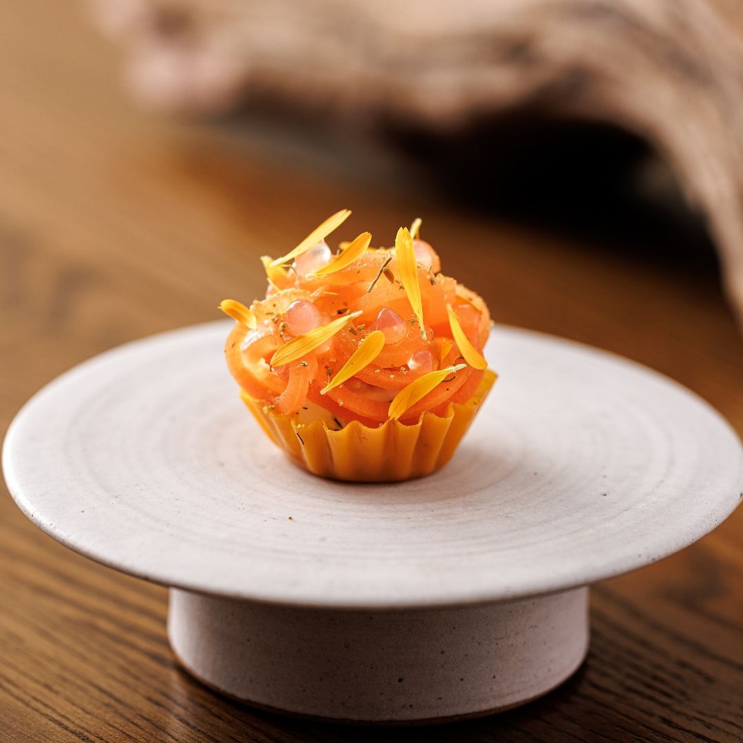 Small and beautiful pastry tartlet containing raw salmon topped with edible flowers