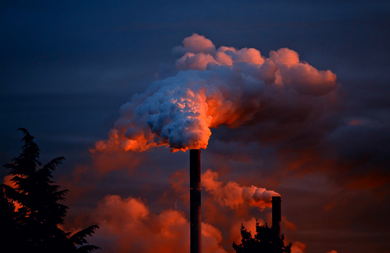 Red pollution coming from smokestacks against dark blue sky