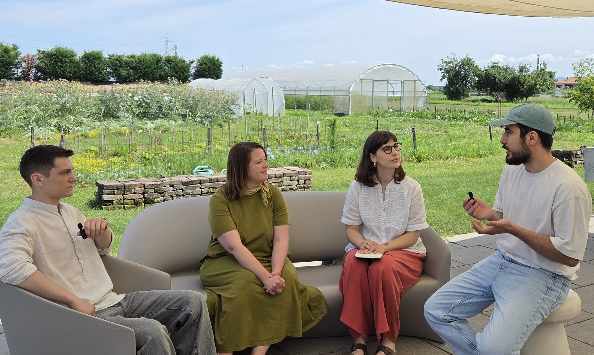 Juliane and Lucia of The SRA speaking with Fabio and Vicenzo of Casa Format under a canopy with the farm in the background