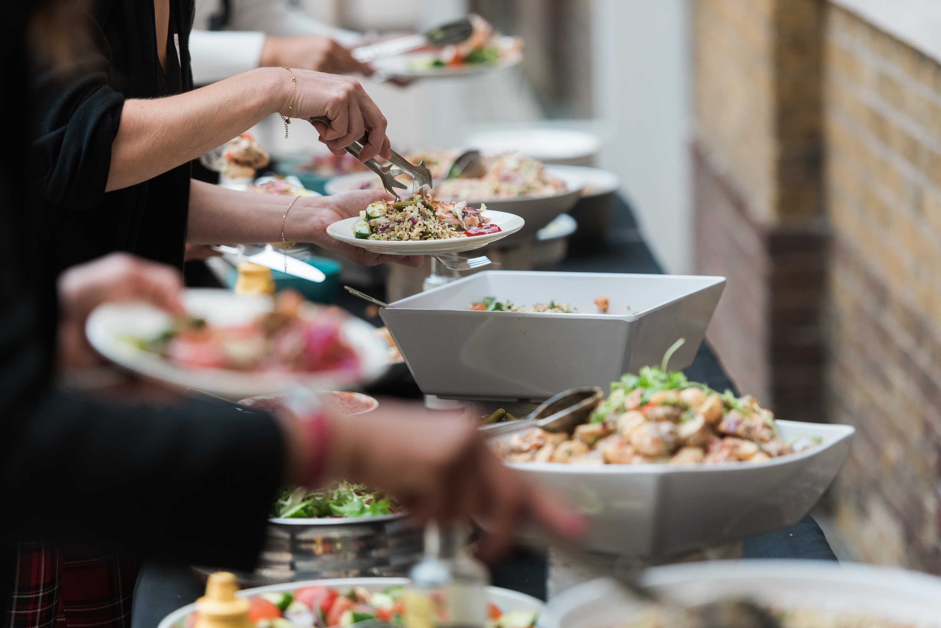 People at a buffet of healthy foods and salads, helping themselves