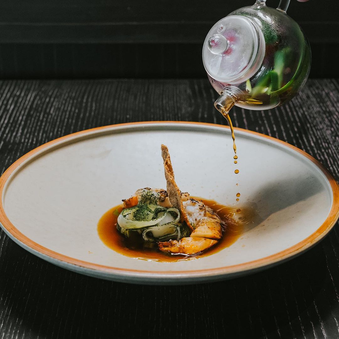 Jug drizzling oil into bowl of beautiful food