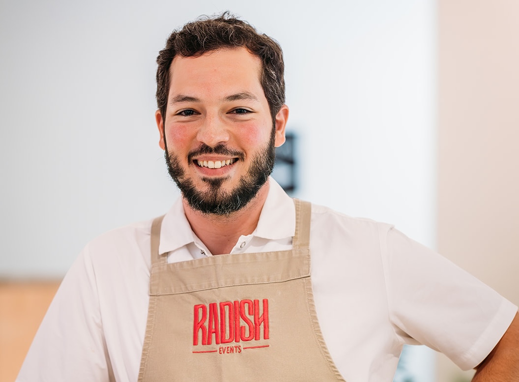 Managing Director of Radish Events Henrique Turra smiling in an apron
