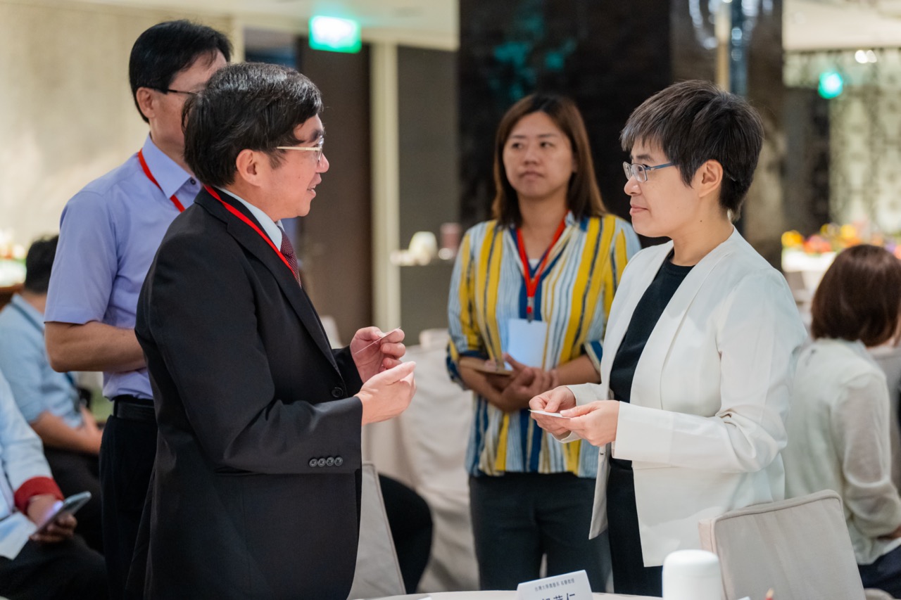 Eunice Yu, Director Of Sustainable Development Center of WNC, talking to other people in suits and lanyards talking in conference room