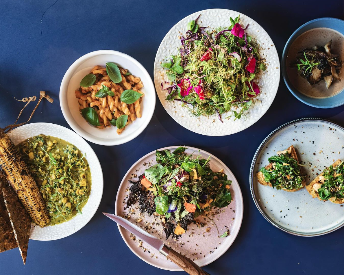 Overhead shot of plates and bowls of food against blue surface