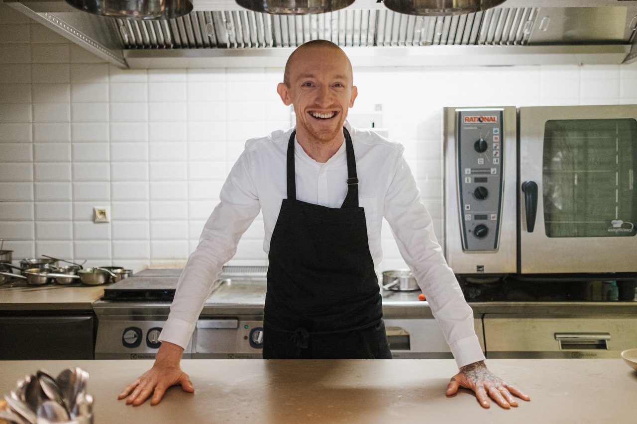 Chef Vojtech Vegh in kitchen smiling at camera