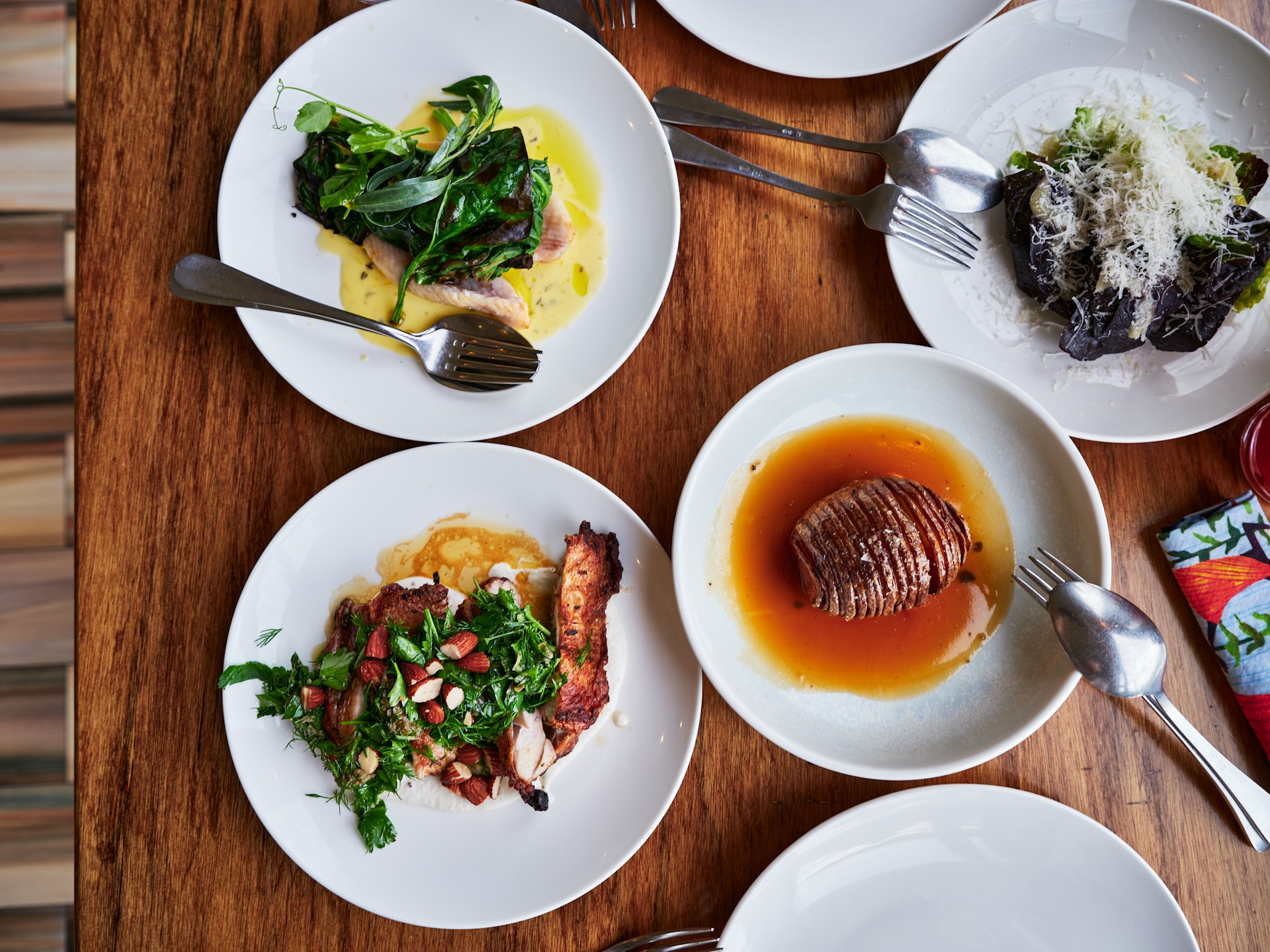 An overhead shot of small plates of different foods on a wooden table