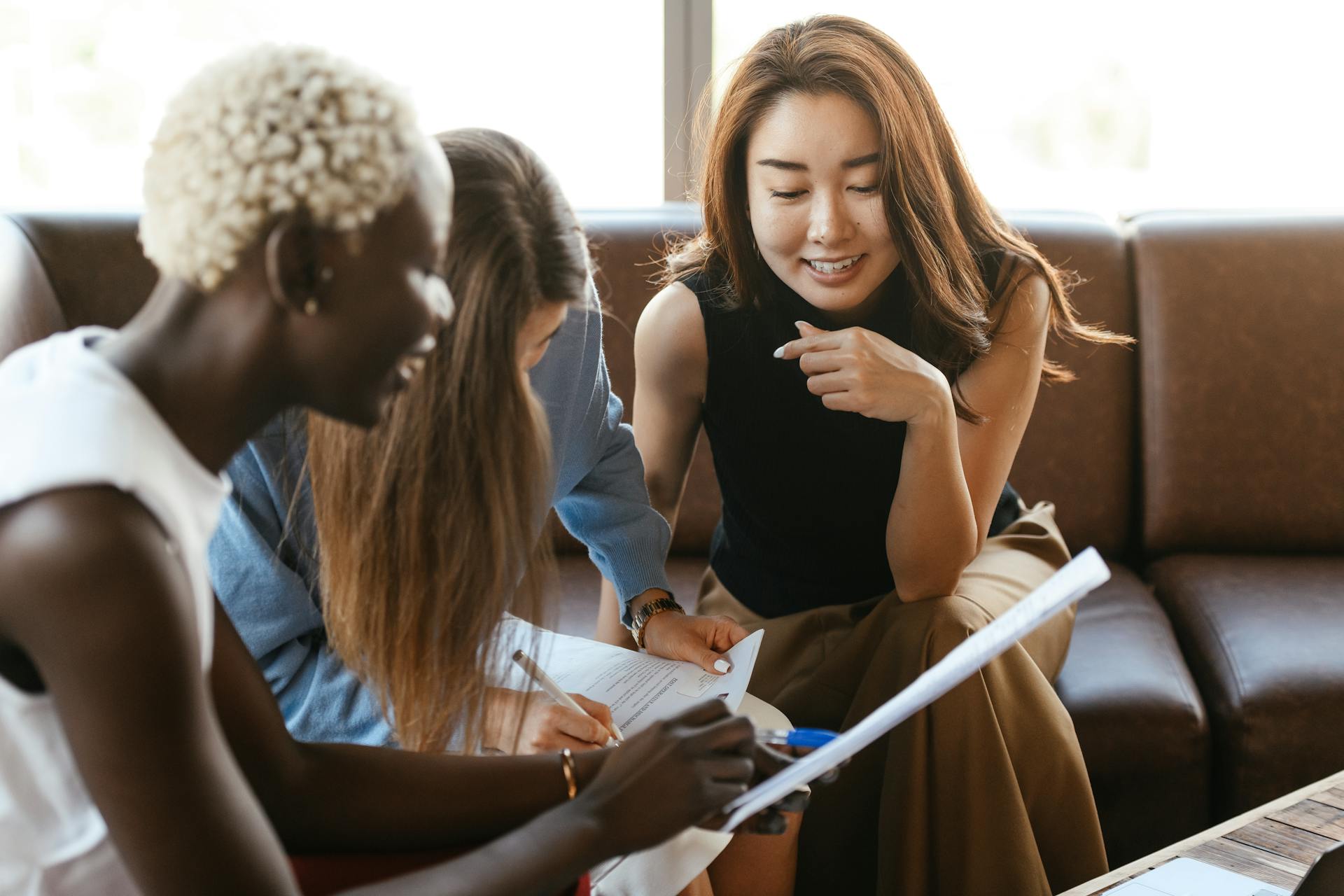 Three women reviewing paperwork together and smiling