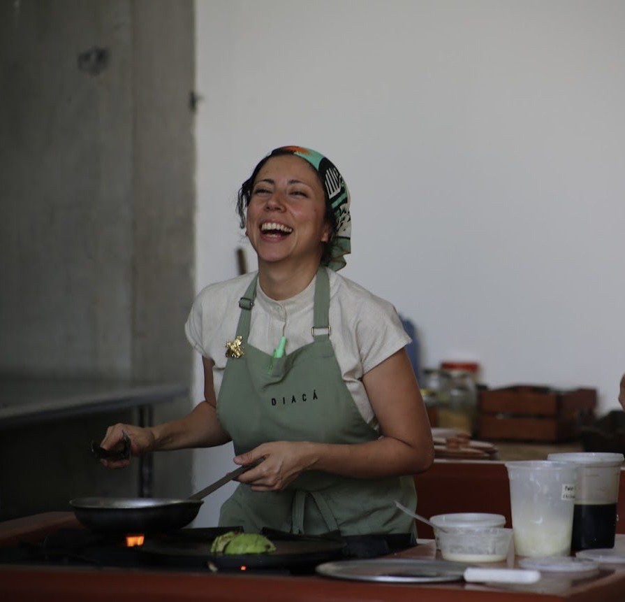Chef Debora Fadul wearing green Diaca apron and laughing in kitchen