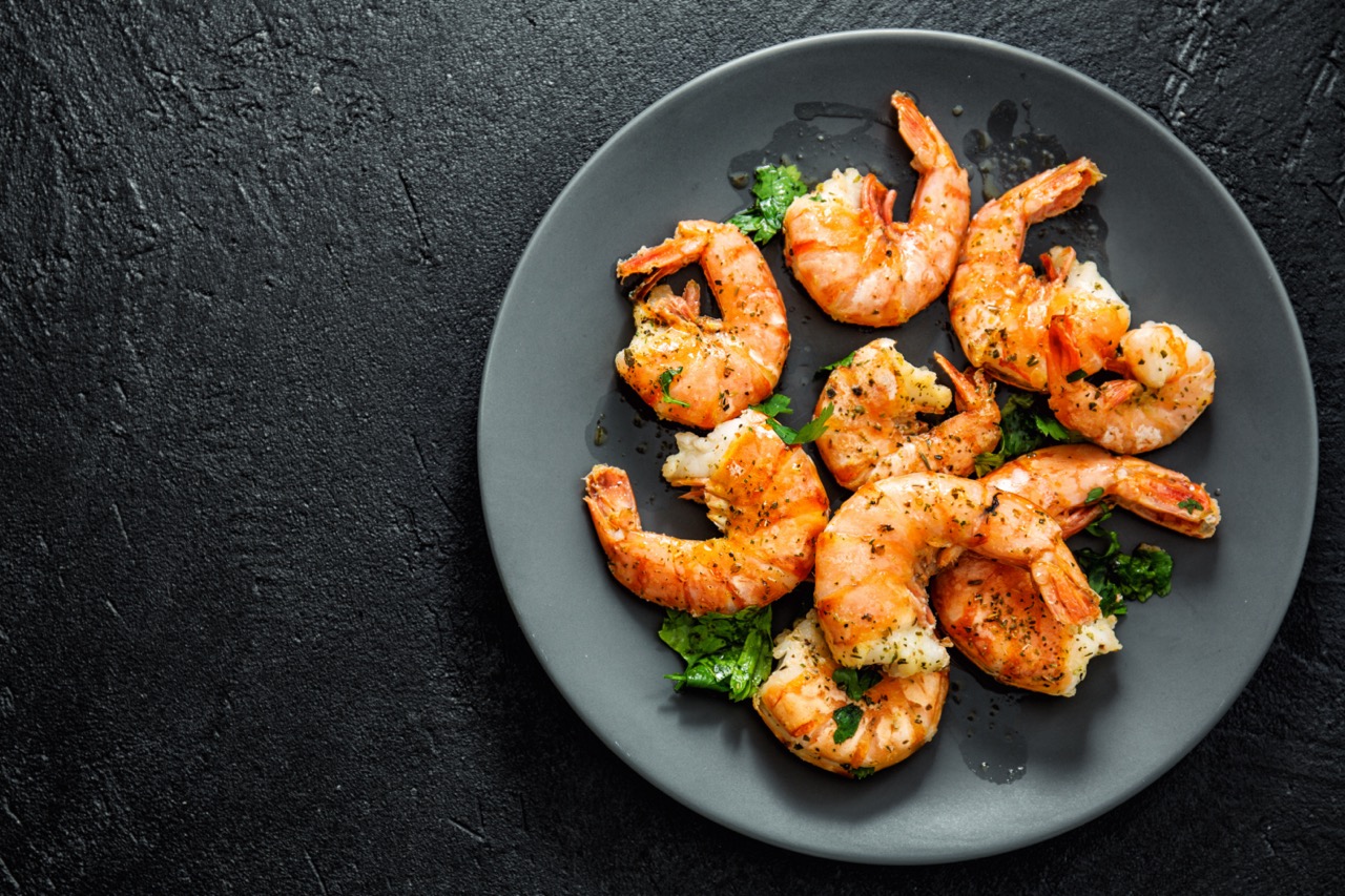 Cooked prawns on a black plate on a black surface