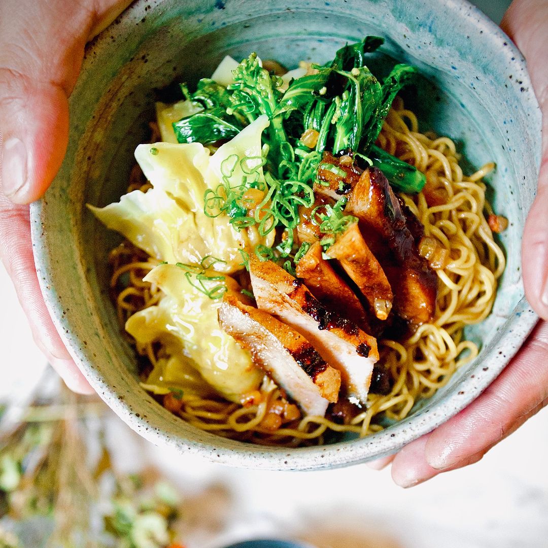 Hands holding bowl of duck noodles