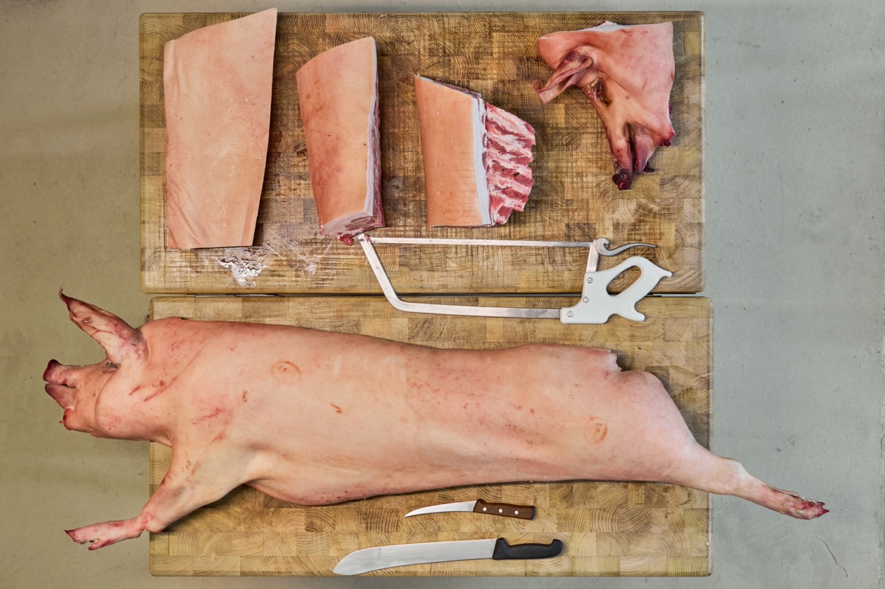 Overhead shot of a whole pig being broken down on a butcher's block