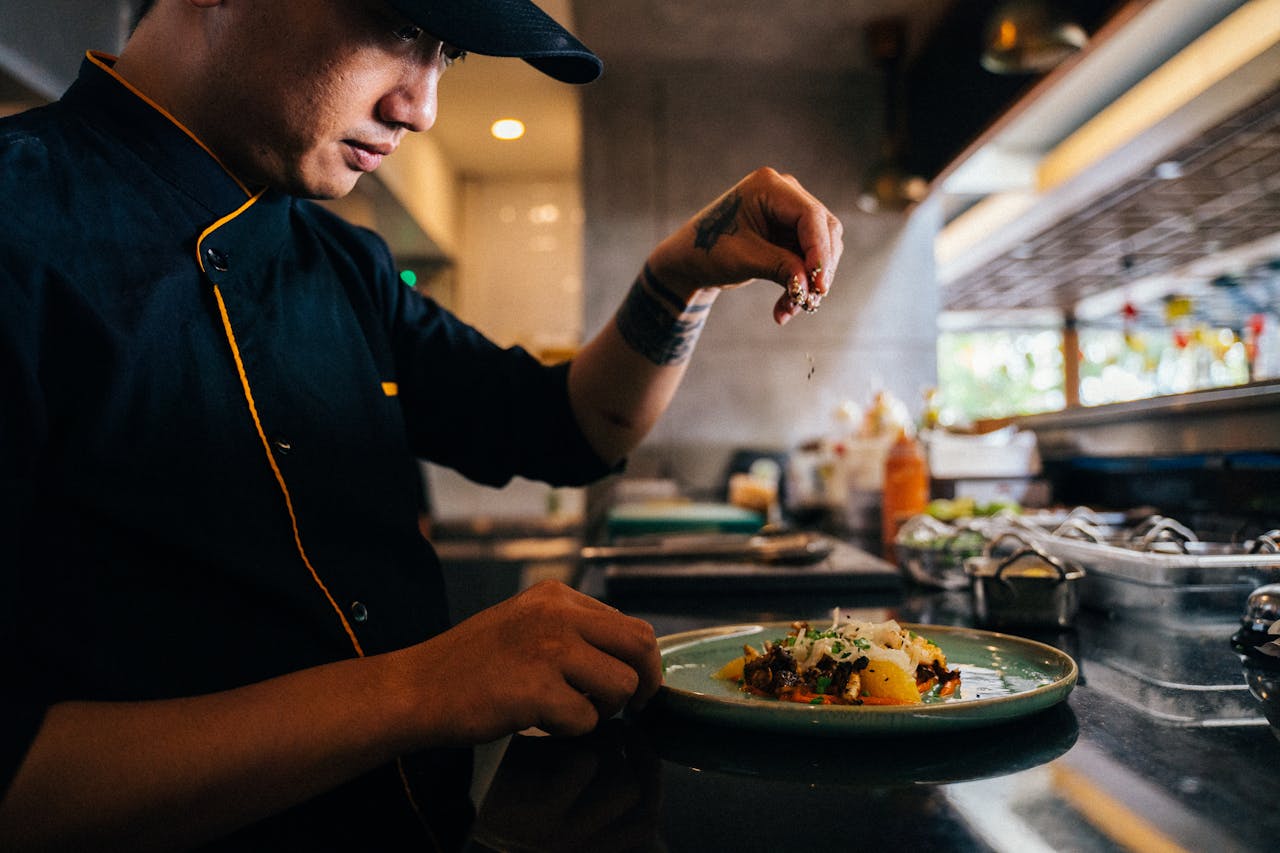 Chef sprinkling garnish on finished dish
