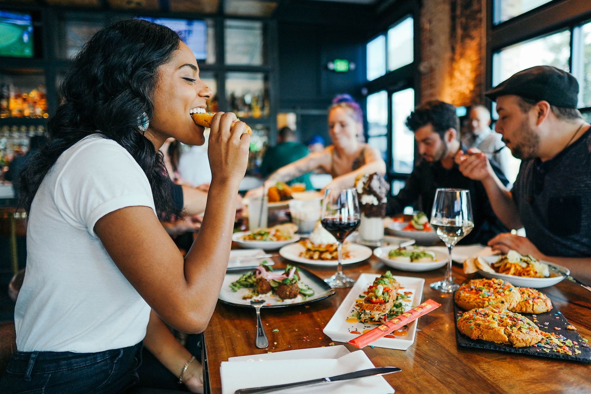 Happy woman eating food at table with other people