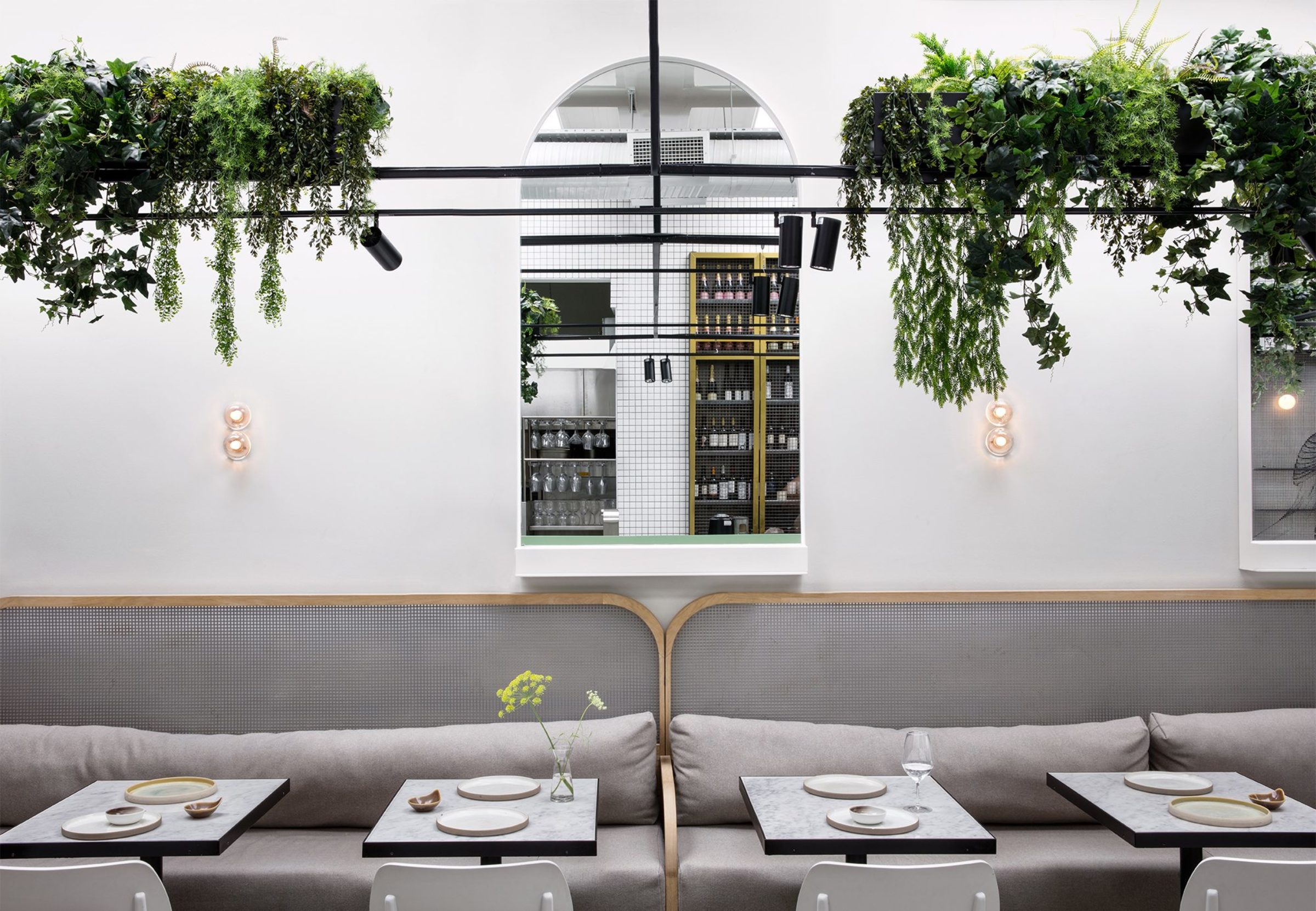 Bright, neutral coloured restaurant interior with white tables and hanging plants