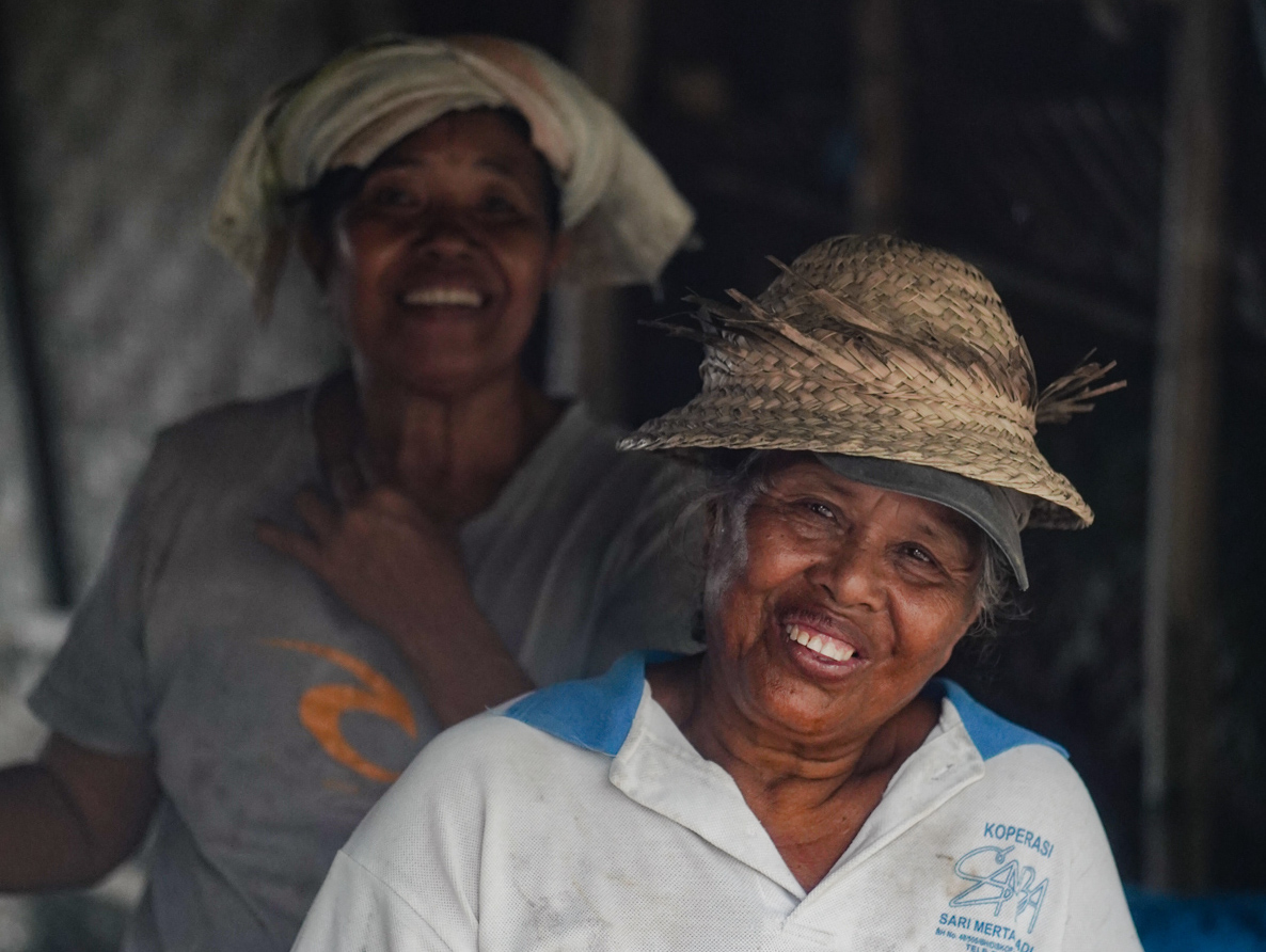 Two native Balinese salt producers posing and smiling for the camera