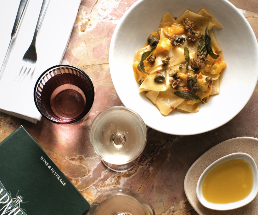 Overhead shot of table with pasta dish, menu and wine glasses at Farmers Marrakech