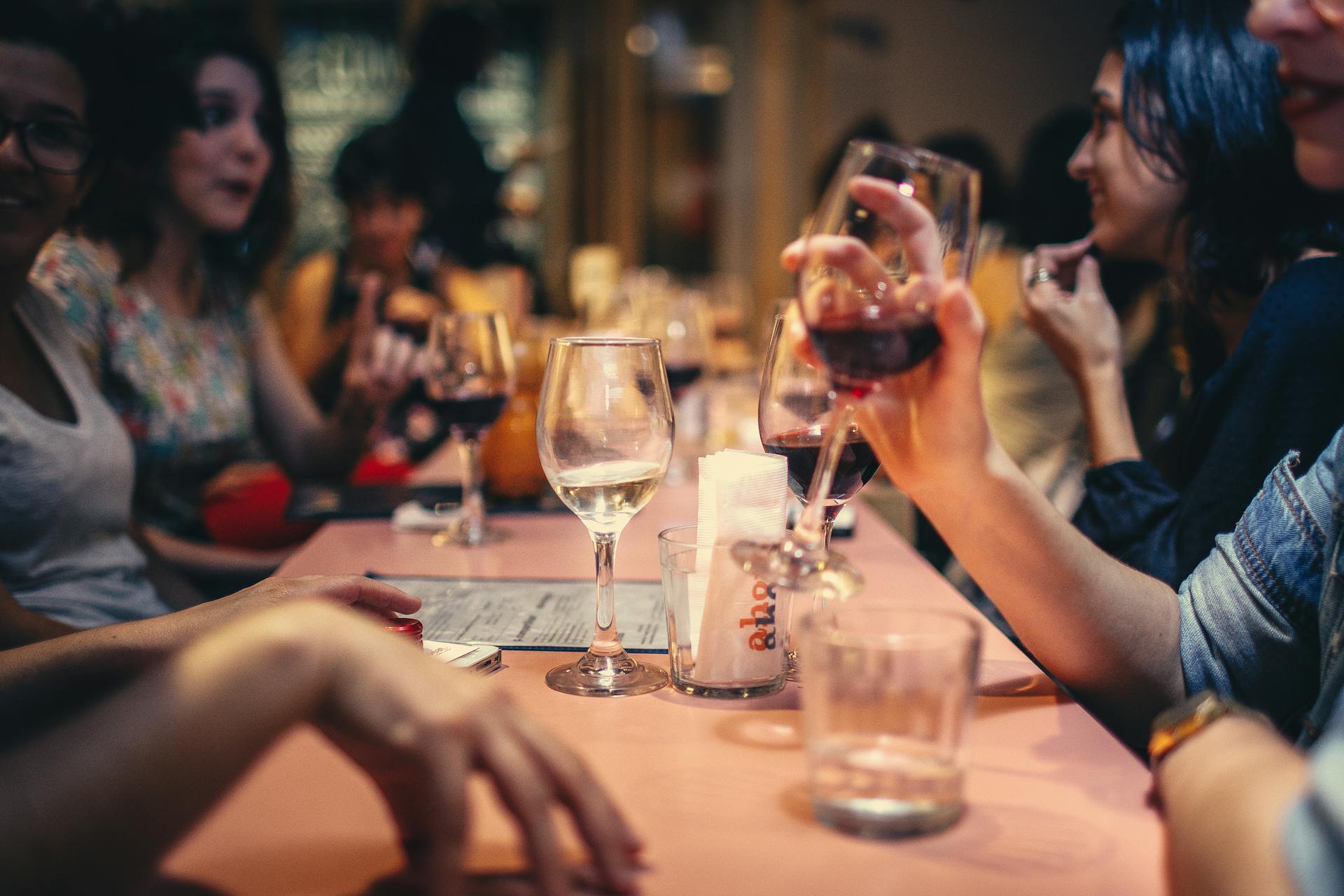 Happy customers drinking wine around tall table