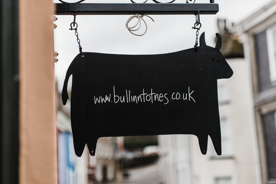 Bull-shaped sign hanging outside The Bull Inn Totnes showing their website address