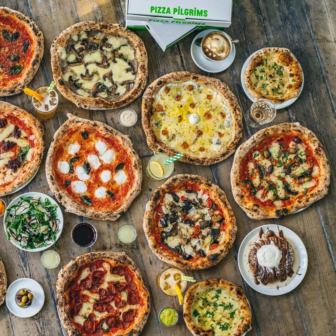 Overhead shot of lots of different pizzas at Pizza Pilgrims on wooden table