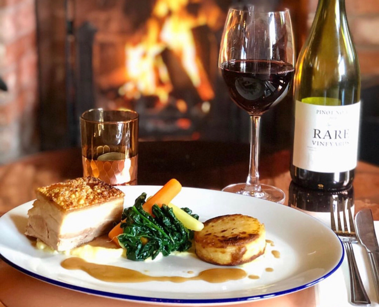 Main course with glass of red wine at Brunning & Price, with fireplace in background