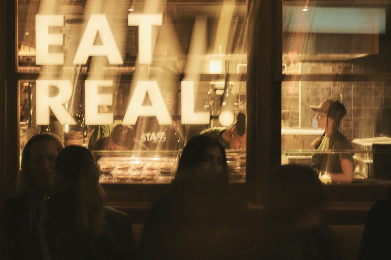 A sign saying "EAT REAL" in the window of an Honest Greens restaurant