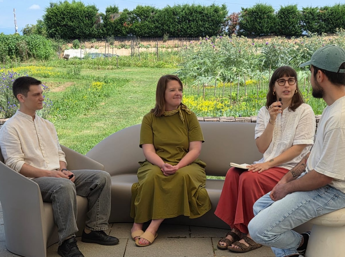 Juliane and Lucia of The SRA speaking with Fabio and Vicenzo of Casa Format under a canopy with the farm in the background