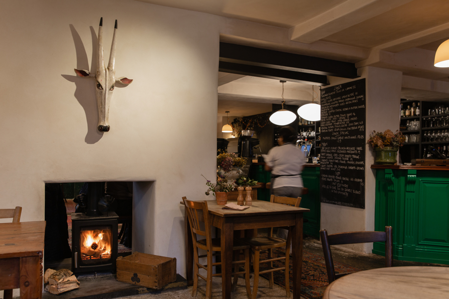 Interior of The Bull Inn Totnes with fireplace and a chef walking in the background