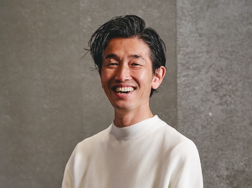 Hideaki Omote of KIGI restaurant, Tokyo, smiling against a grey background