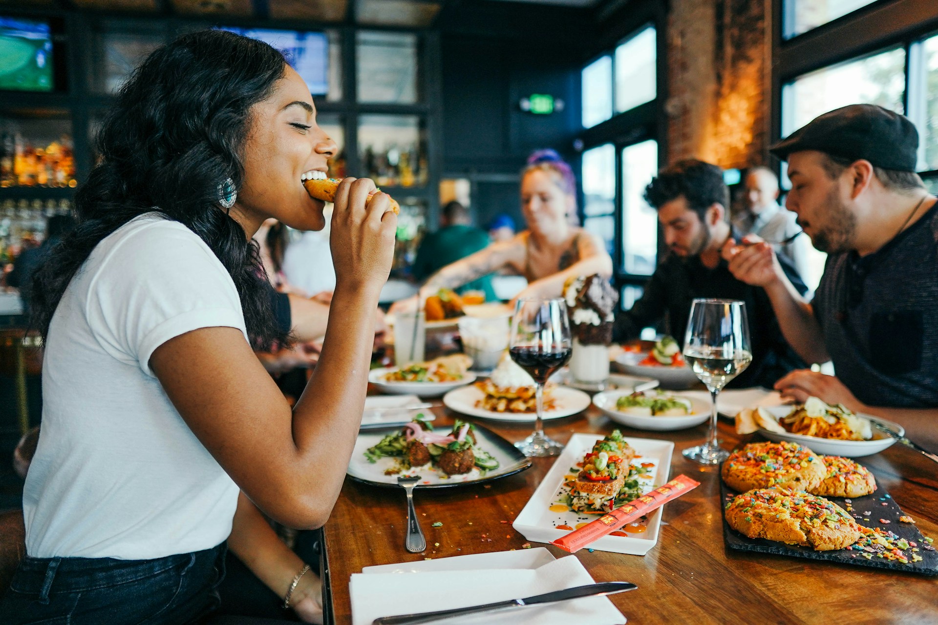 Happy woman eating food at table with other people