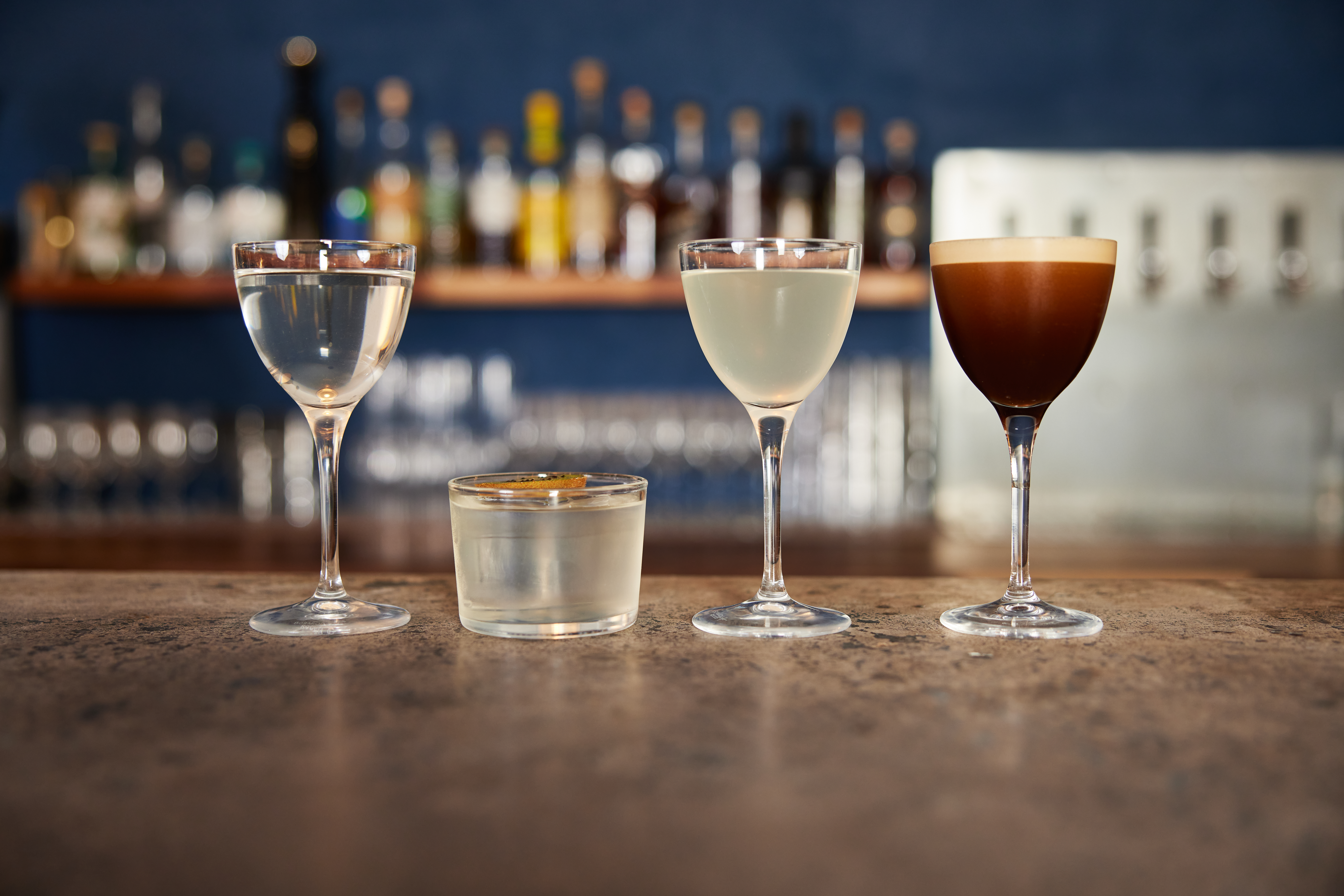 Four cocktails on a bar counter.