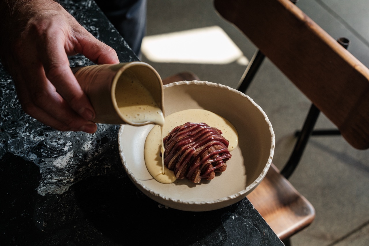 Hand pouring sauce from jug into dessert plate