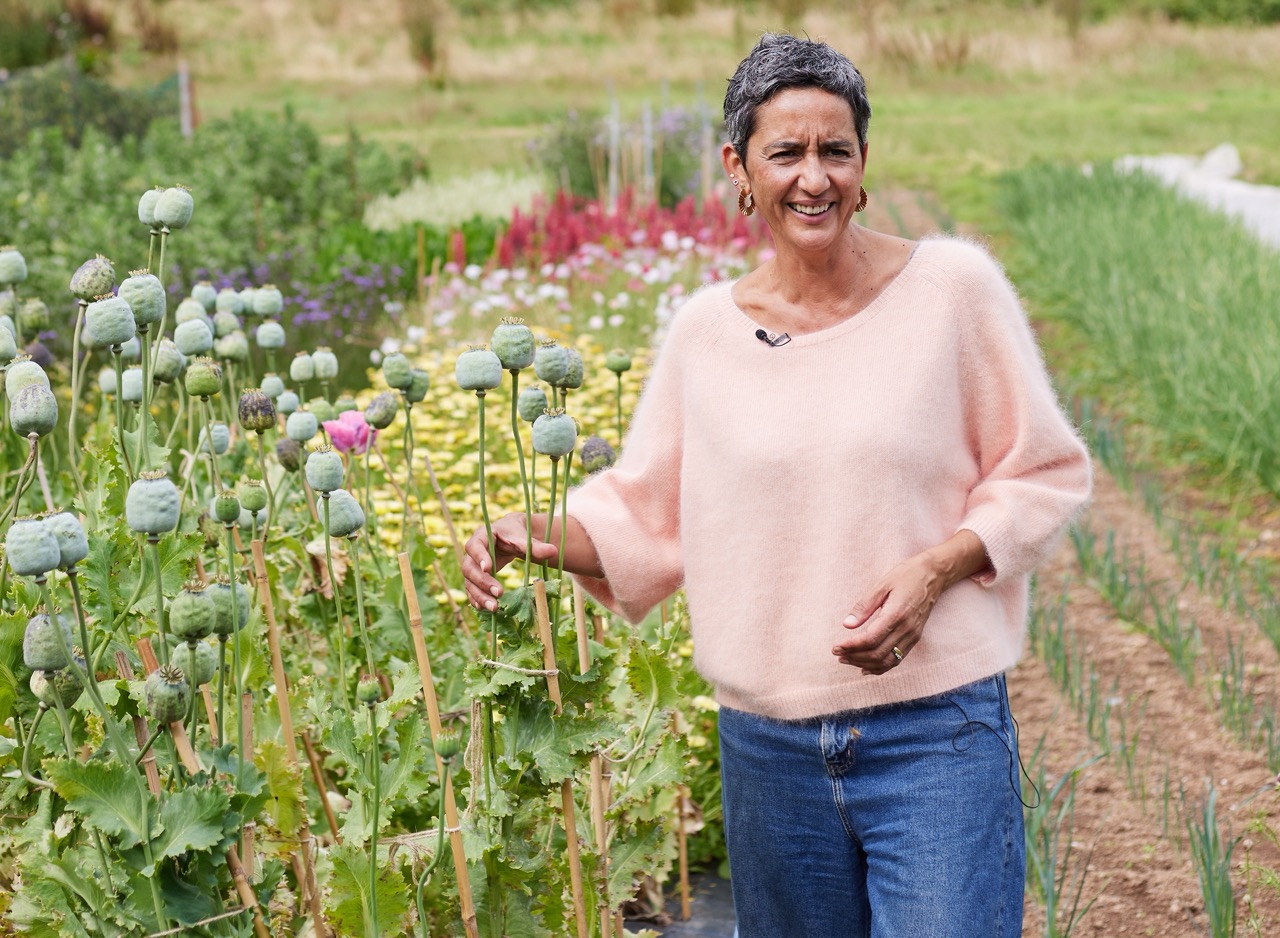 Geetie Singh Watson, owner of The Bull Inn in Totnes, standing in a field reaching out to tall flowers