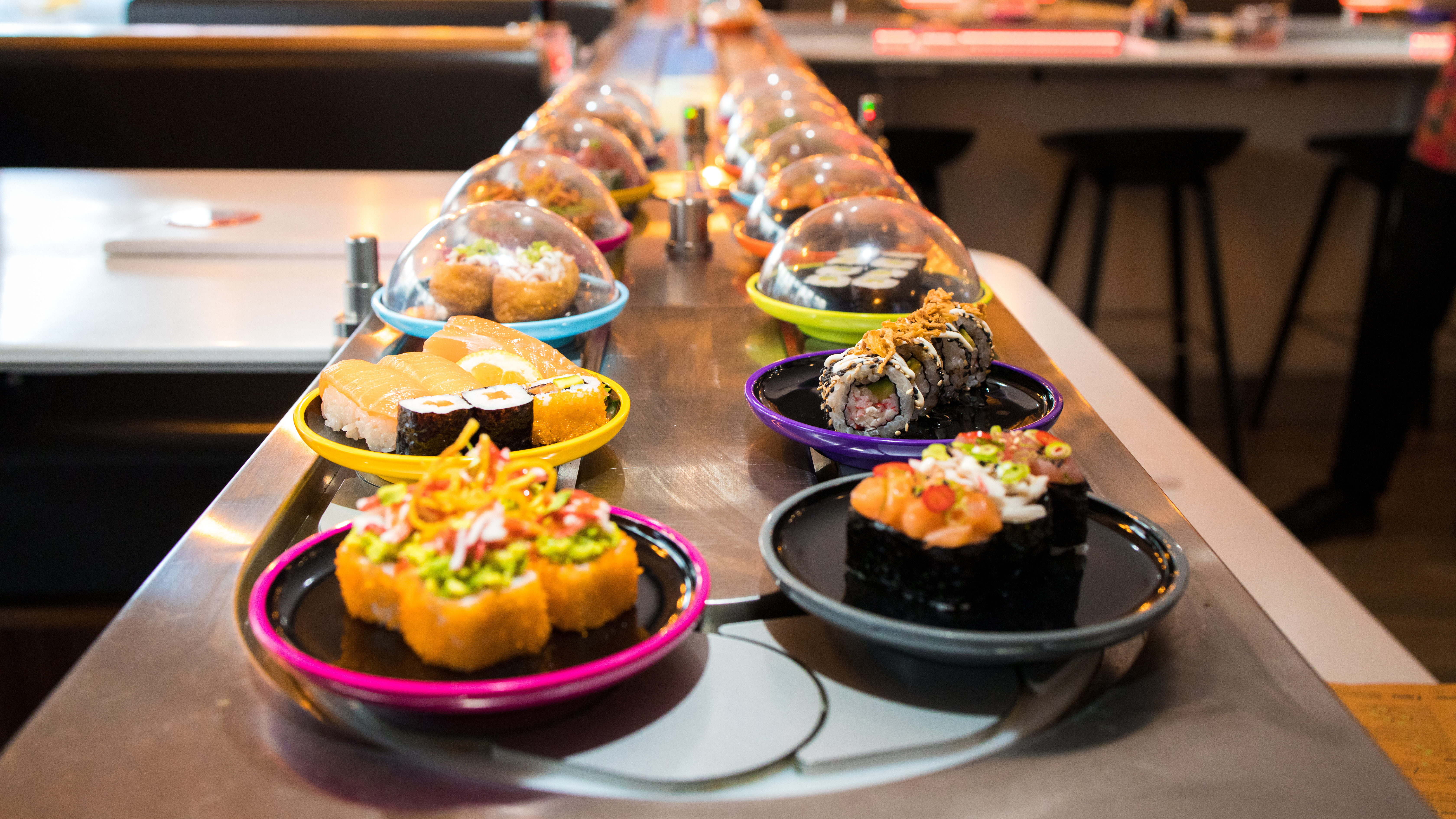 Colourful dishes of sushi on conveyor belt at Yo! Sushi
