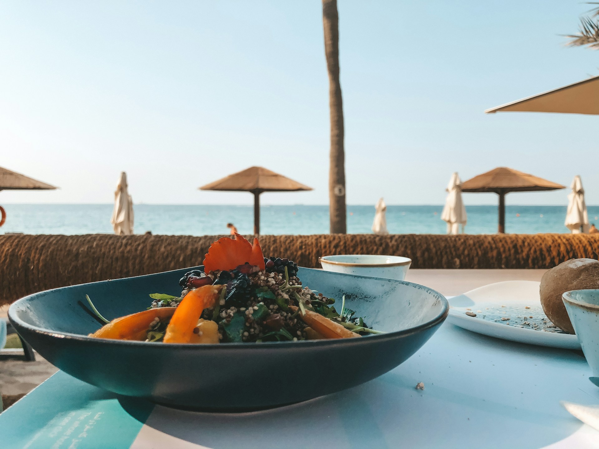 A meal on a blue table outdoors at a hotel overlooking the ocean