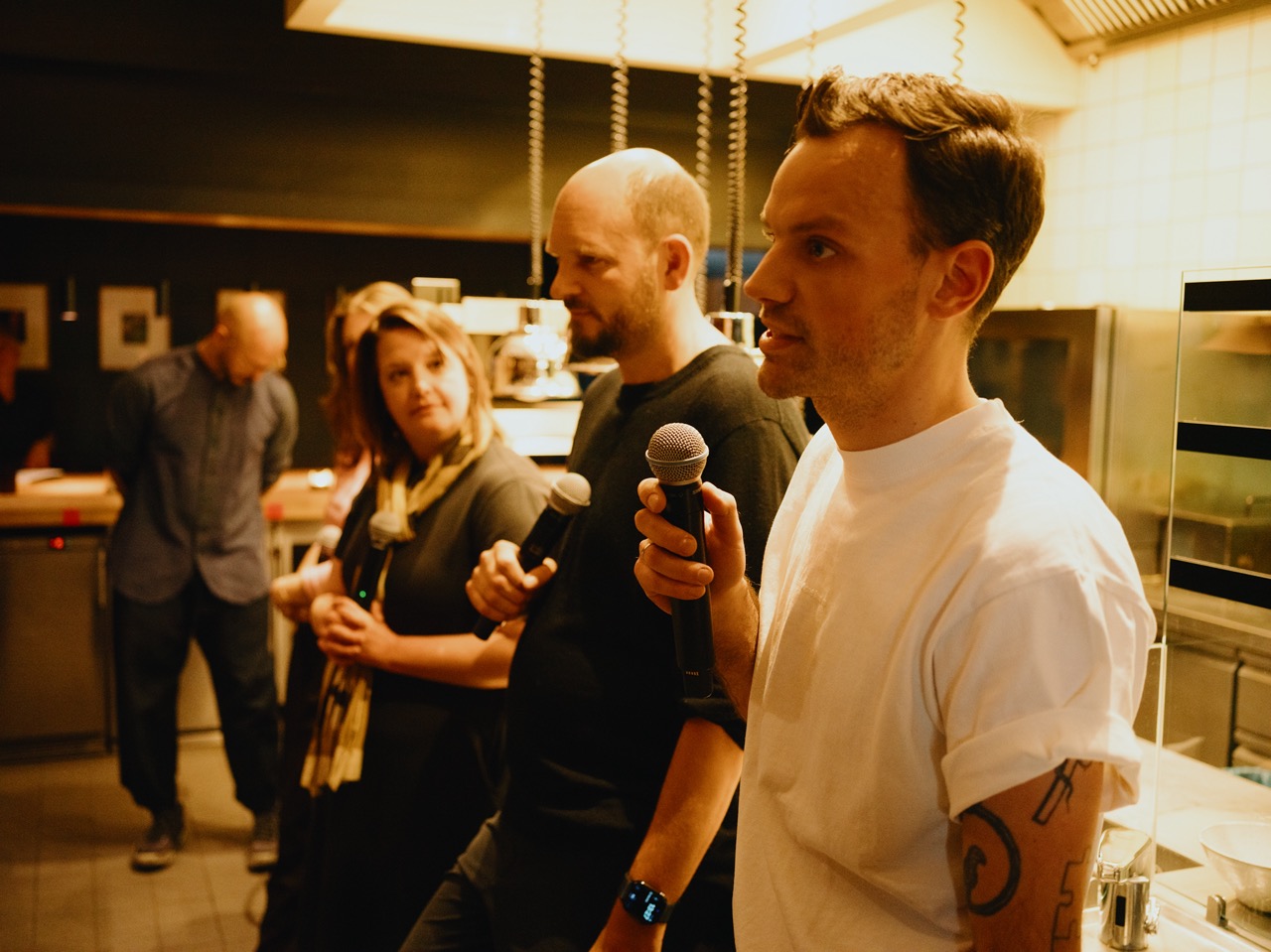 Patrick Wodni speaking into microphone at Nobelhart & Schmutzig, Berlin, with other panellists in the background