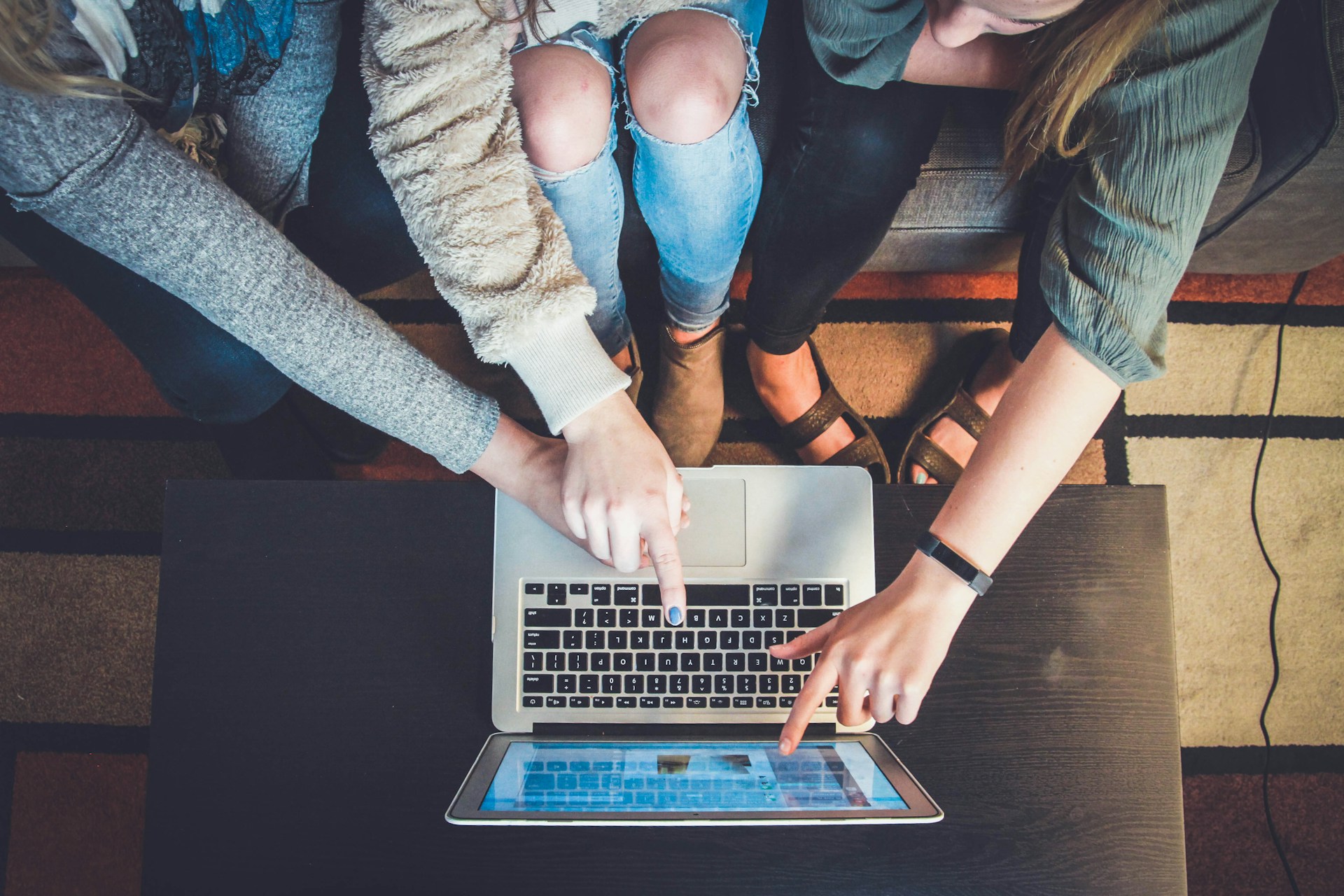 Overhead shot of people pointing at a laptop