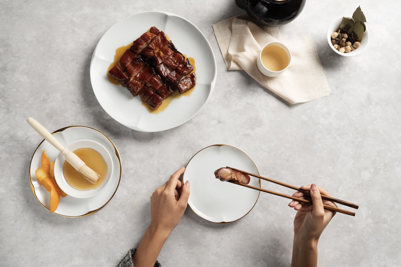 Overhead shot of someone eating a dish of roasted pork using chopsticks