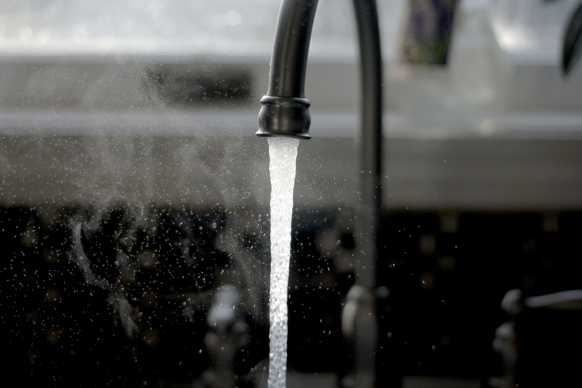 Water pouring from black tap into sink