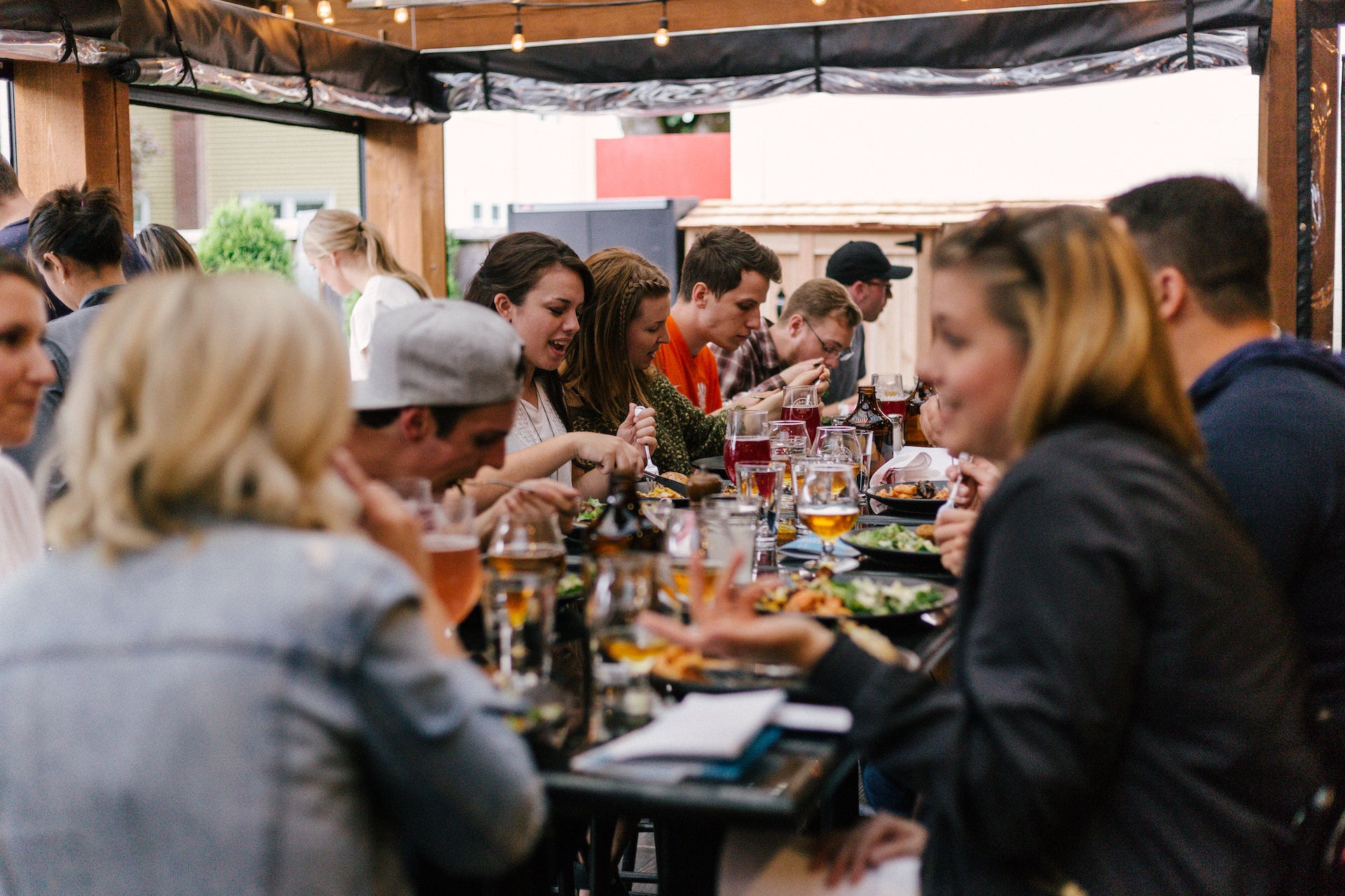 Happy customers at long table eating, drinking and talking
