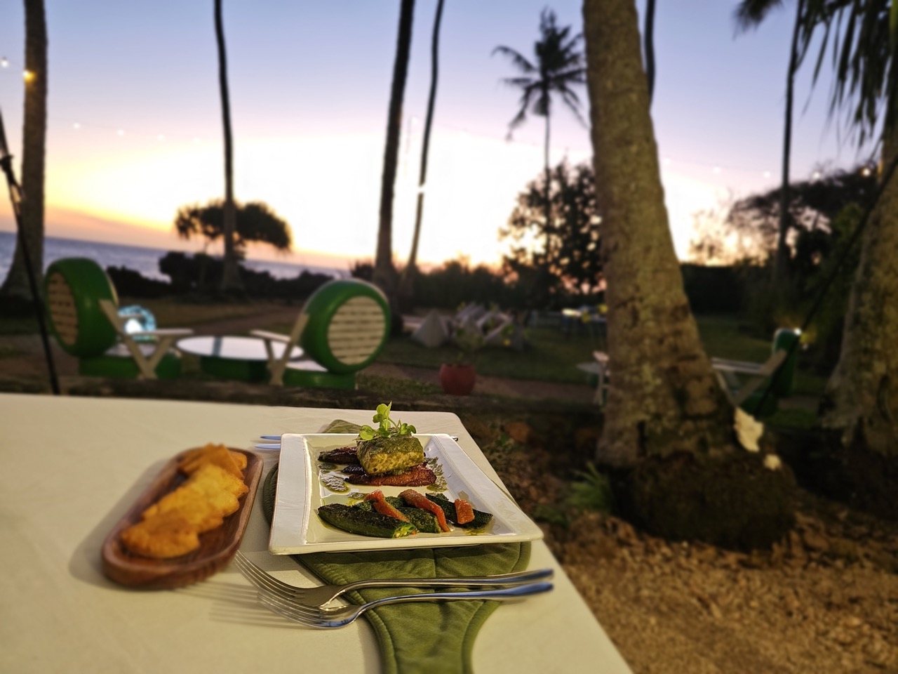 A table of food at Fahari Off The Grid with palm trees and the sunset in the background