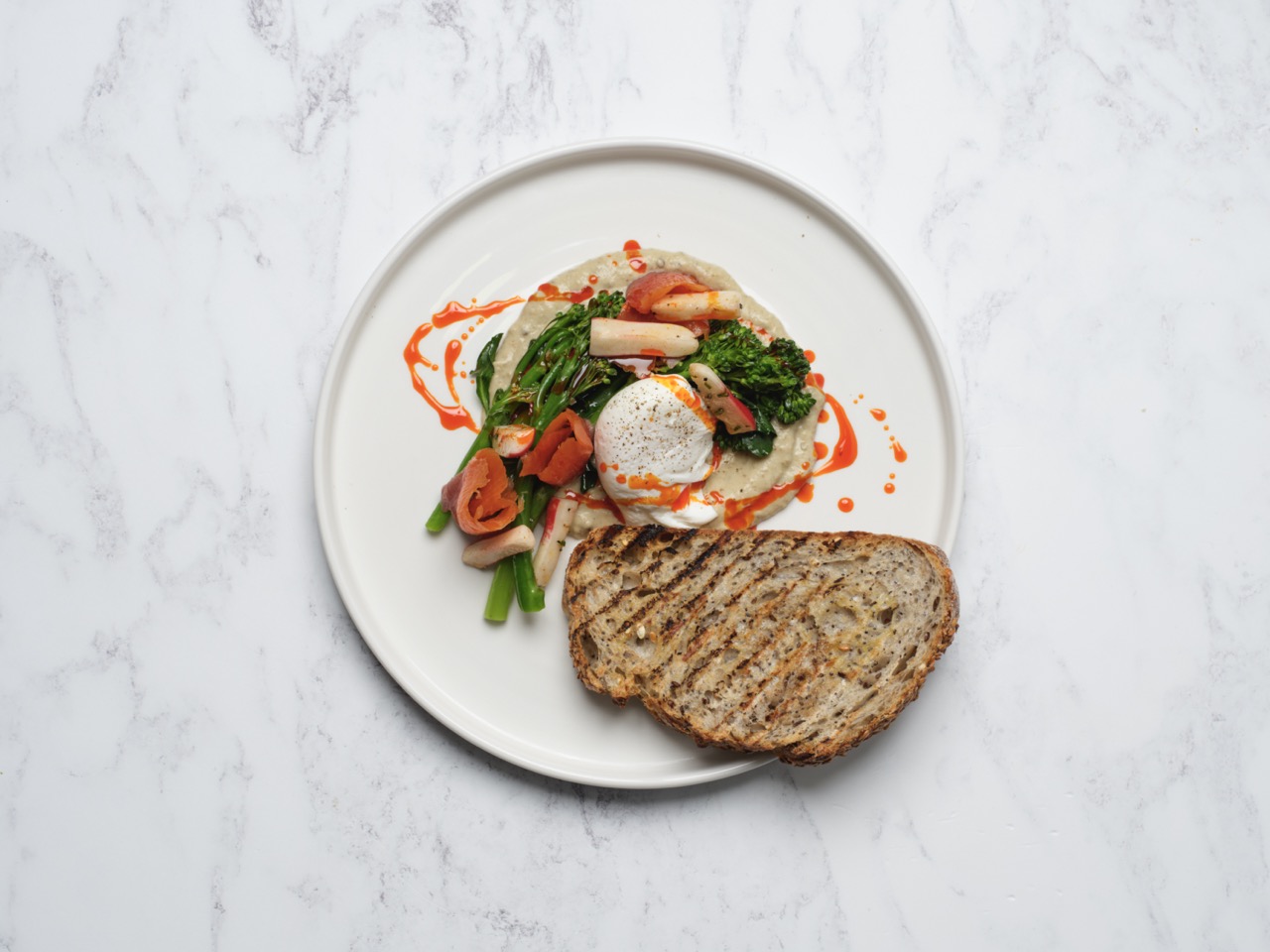 Overhead shot of poached eggs, hummus and vegetables with wholemeal toast at Restaurant Associates