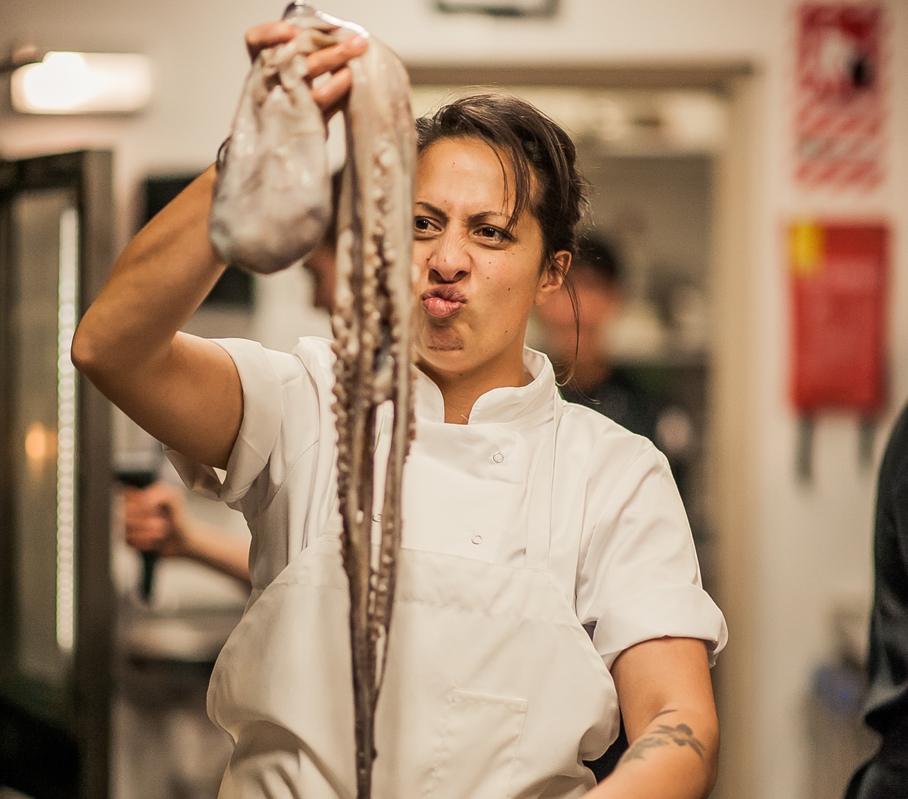 Chef Monique Fiso in kitchen holding up big octopus